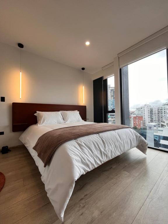 a bedroom with a large bed with a large window at Apartamento de Lujo en Quito in Quito