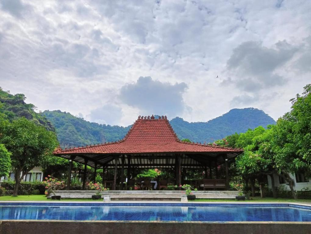 a pavilion with a roof next to a swimming pool at The Joglo By The Beach Pemuteran Bali in Pemuteran