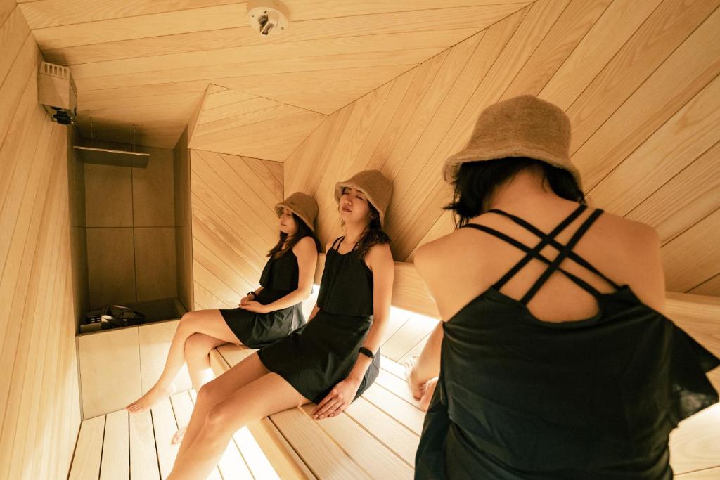 three women sitting in a sauna looking in a mirror at 脈 -MYAKU PRIVATE SAUNA- in Fukuoka