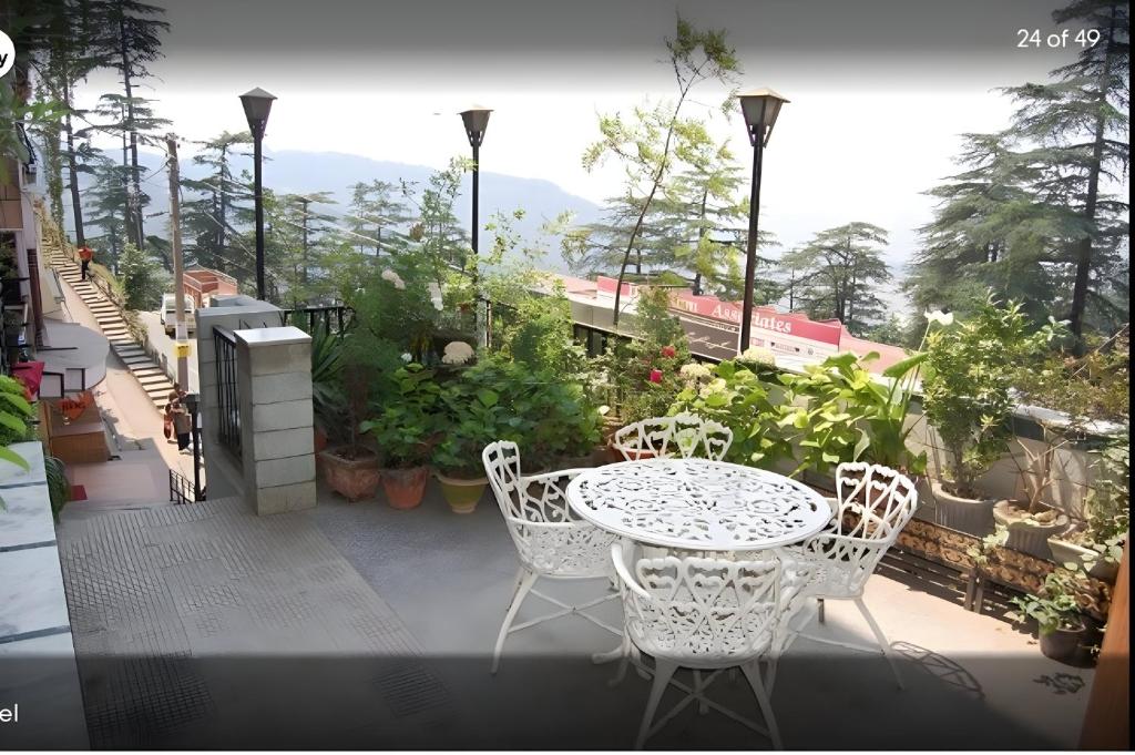 a patio with a table and chairs on a balcony at Hotel Ganga Near Mall Road in Shimla
