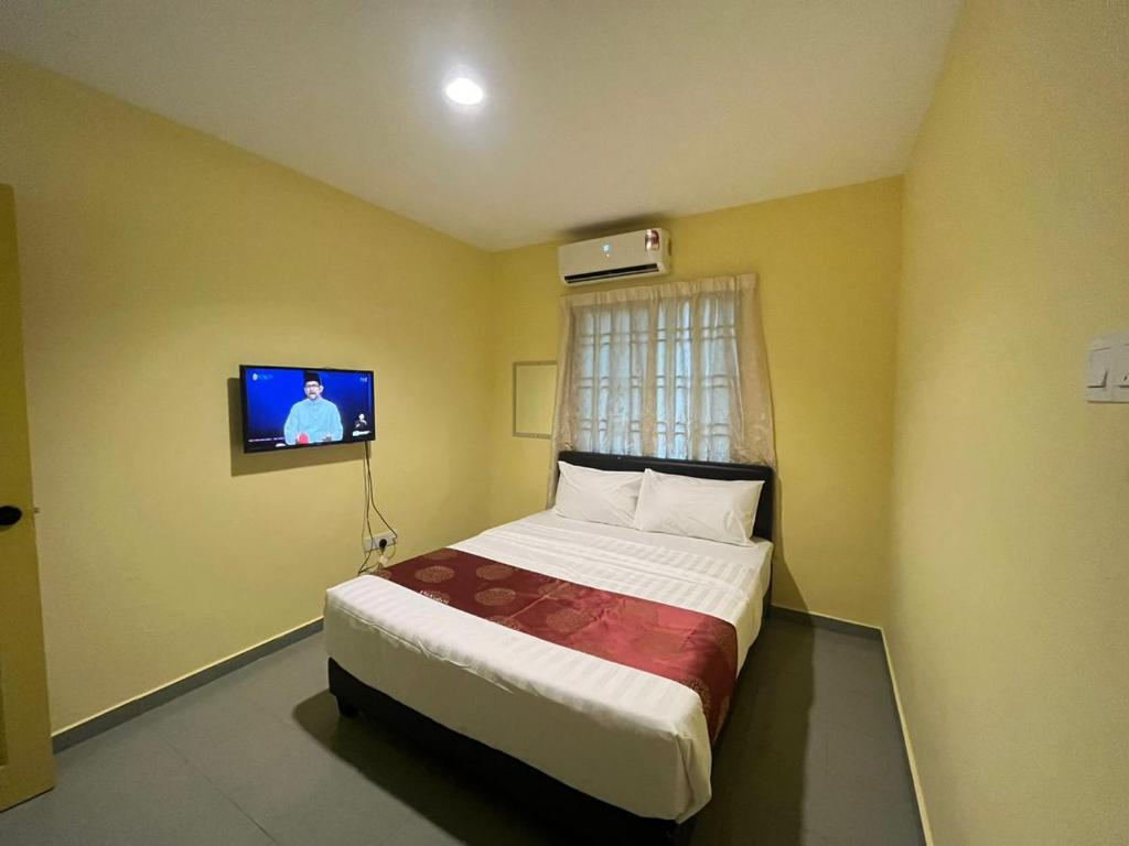 a bedroom with a bed with a tv on the wall at Rahmah Sojourn Center in Johor Bahru