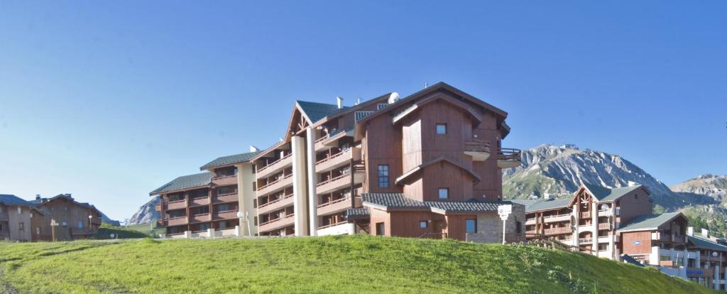 un grand bâtiment au sommet d'une colline herbeuse dans l'établissement Madame Vacances Lodges des Alpages, à La Plagne