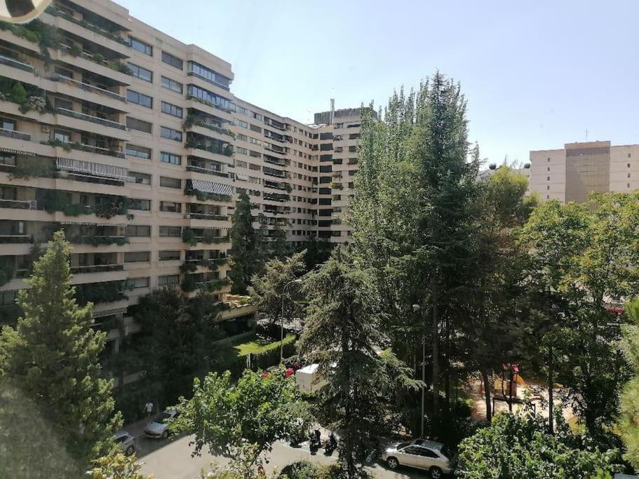 un grand immeuble avec un parking et des arbres dans l'établissement Zona Norte Vistas, à Madrid