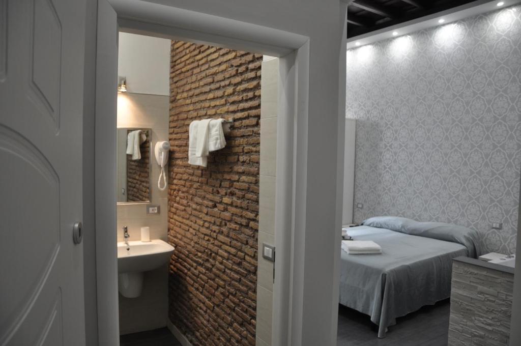1 dormitorio con 1 cama, lavamanos y pared de ladrillo en Imperial Relais, en Roma