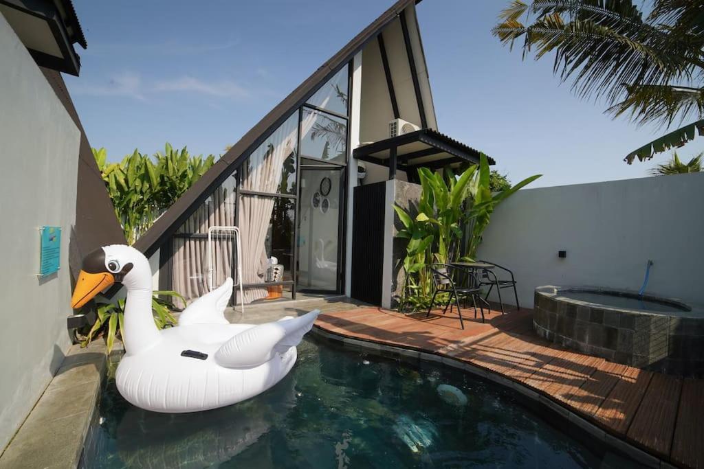 a swan float in the water next to a house at Ubu Villa Coconut 102 - in Yogyakarta in Yogyakarta