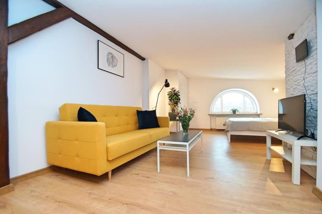 a living room with a yellow couch and a tv at FV/ Mariacka 7 - Studio apartment -Katowice in Katowice