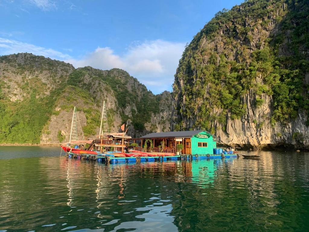 a boat in the water next to a mountain at Eco Floating Farm Stay Cai Beo in Cat Ba