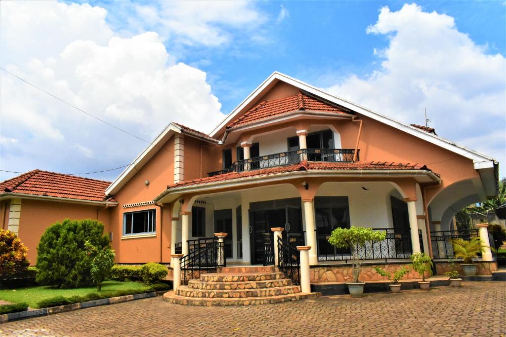 a large orange house with a balcony and stairs at Beautiful home opposite Speke Resort Munyonyo near Lake Victoria in Kampala