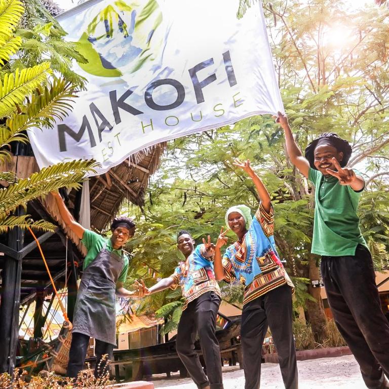 a group of people holding a sign in front of a building at Makofi Guest House in Nungwi