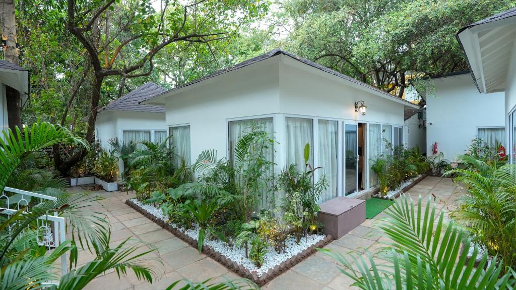 a white house with plants in front of it at Swimup - Suites with private pool , Vagator in Vagator