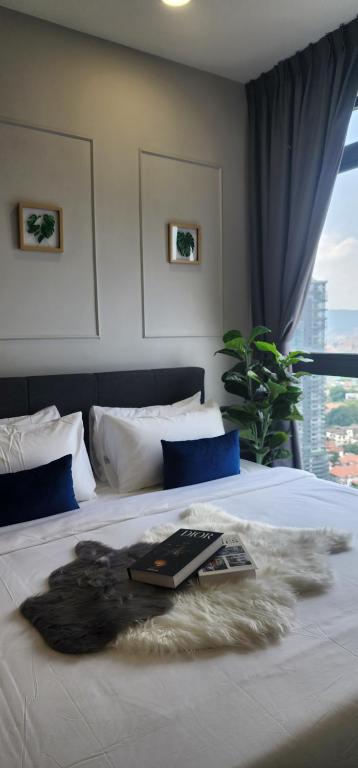 吉隆坡的住宿－Neu Suites @ 3rdNvenue by Perfect Host，一间卧室配有一张床,上面有一本书
