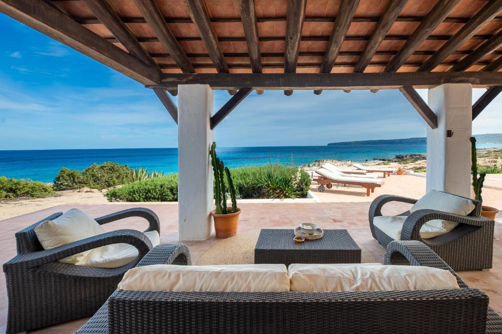 eine Terrasse mit Stühlen, einem Tisch und Meerblick in der Unterkunft Senrramada in Playa Migjorn