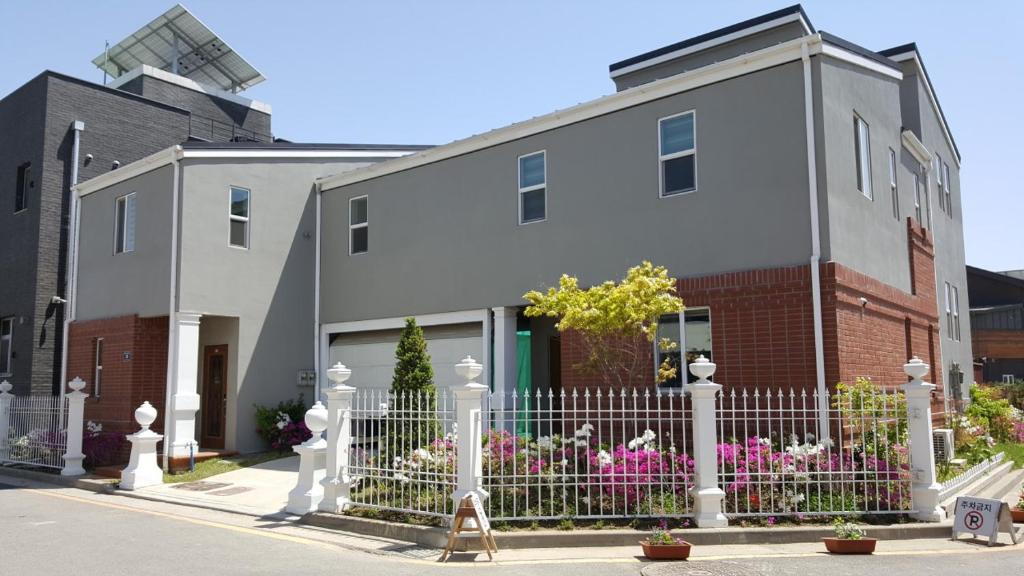 a white house with a fence in front of it at All In One Guesthouse in Incheon