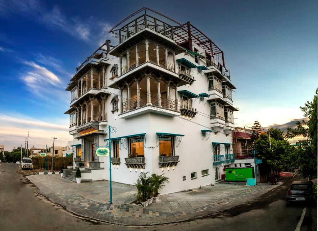 a tall white building with balconies on a street at Khamma Ghani A Boutique Hotel in Udaipur