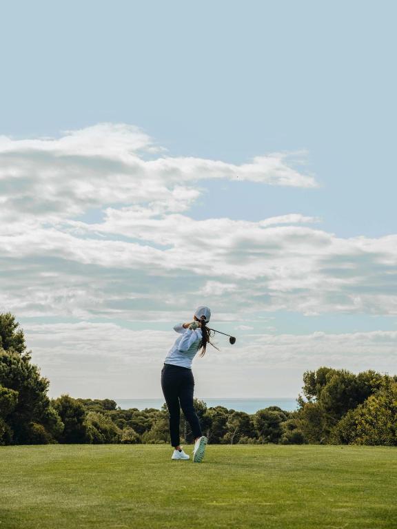 a woman swinging a golf club on a field at Meliá Lloret de Mar in Lloret de Mar