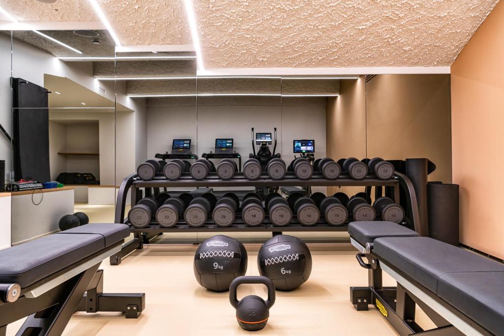 a gym with several rows of dumbbells in a room at Palazzo Tirso MGallery Cagliari in Cagliari