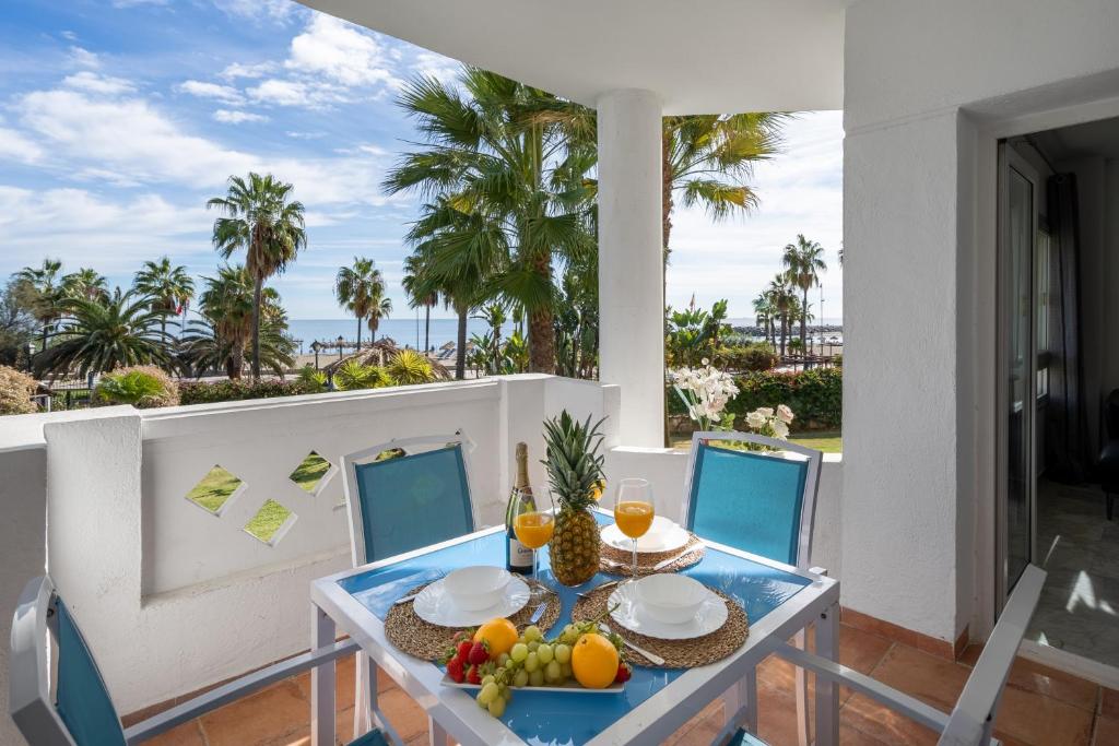 un tavolo con frutta su un balcone con palme di First Line Apartment in Puerto Banus a Marbella