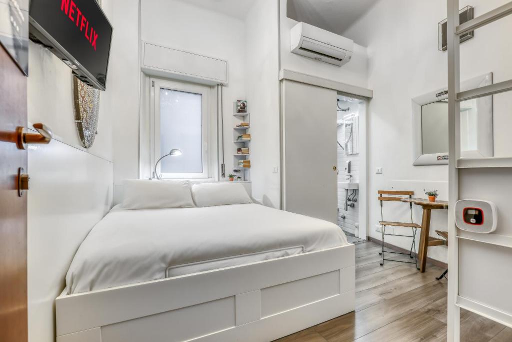 a white bedroom with a bed and a window at ANGOLO AL PONTE micro appartamento in pieno centro in Pavia