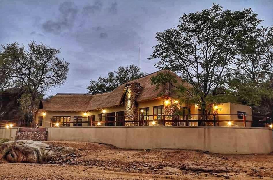 uma casa com um telhado de palha com luzes em Selwane Nature Reserve em Gravelotte