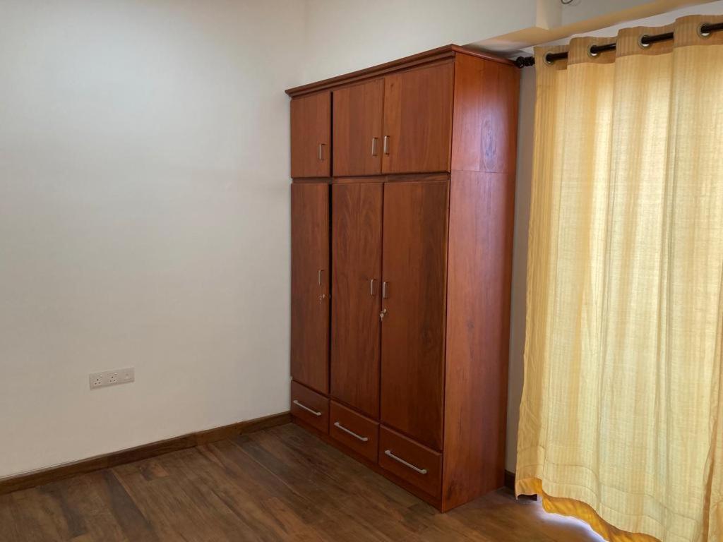 um quarto com um armário de madeira e uma cortina em Alfred apartments em Colombo