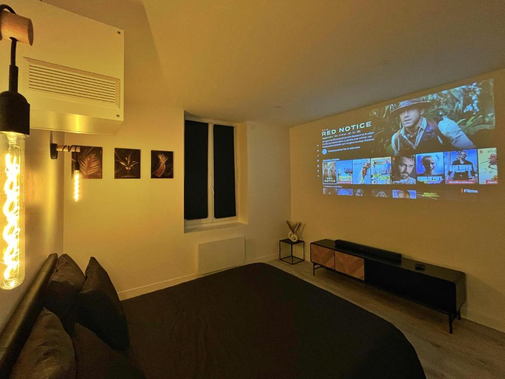 uma sala de estar com uma grande televisão na parede em Suite de JIJI - Suite Chic Spa - Home-Cinéma & Netflix - Wi-fi em Saint-Étienne