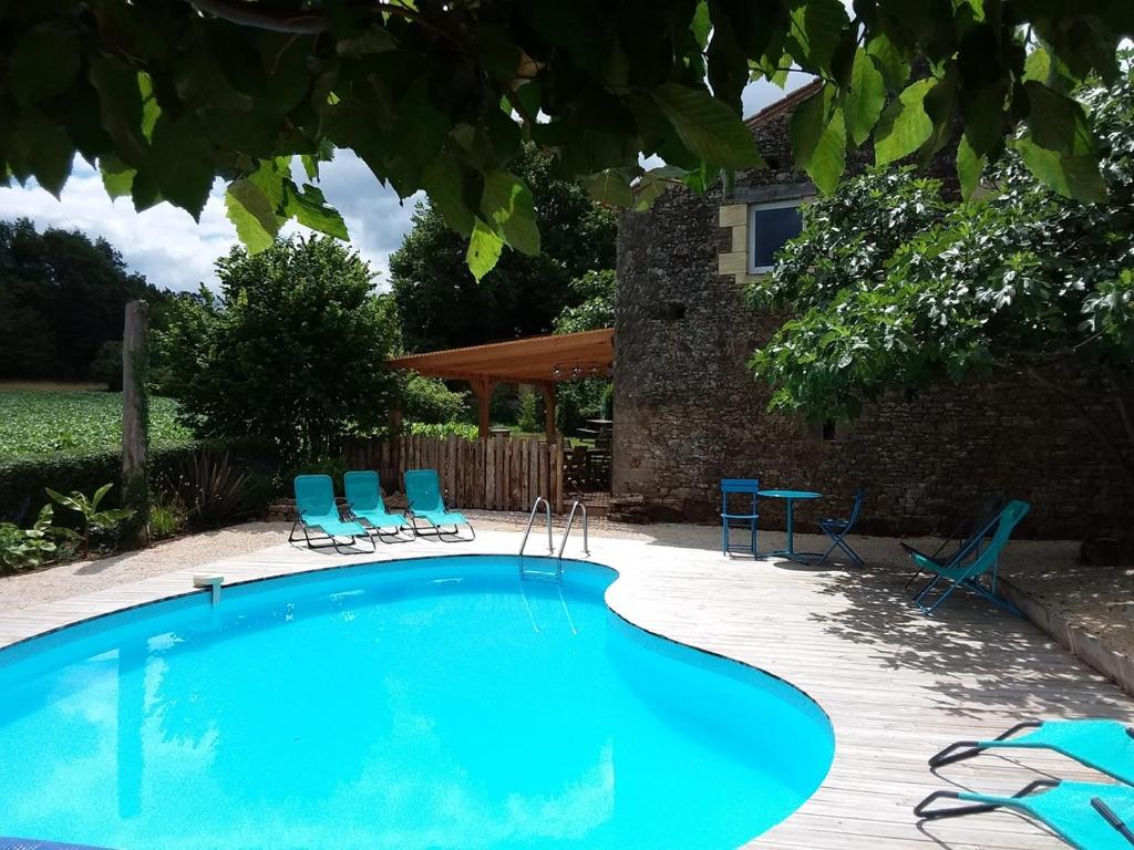 a swimming pool with blue chairs and a house at Gîte des Champs Lalaurie in Sauveterre-la-Lémance