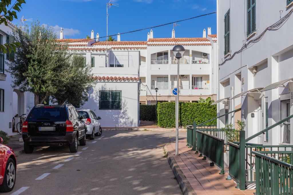 a street with cars parked in front of a building at Cala en Blanes Park in Cala en Blanes