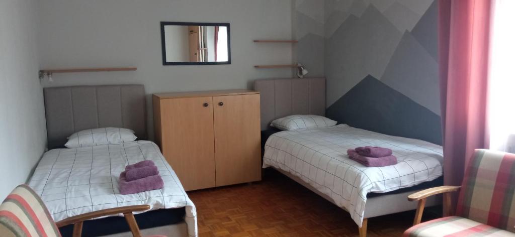 2 posti letto in una piccola camera con asciugamani viola di BranySol Apartman a Novi Sad