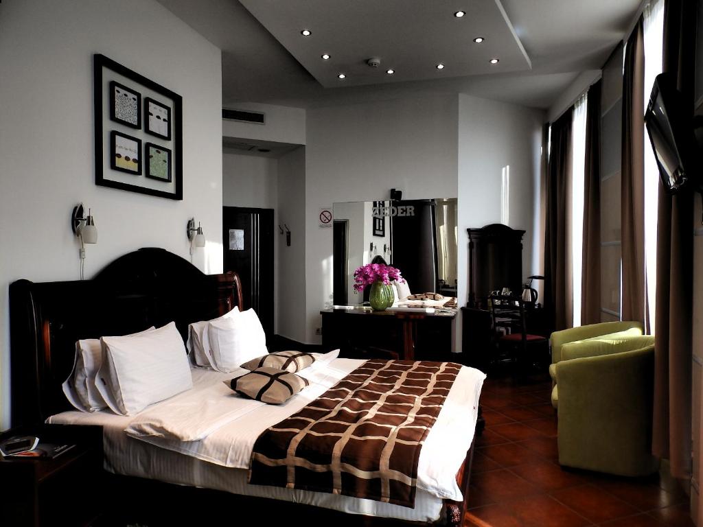 a bedroom with a large bed in a room with windows at Hotel Zeder Garni in Belgrade