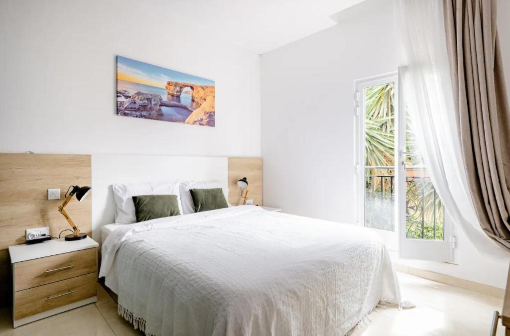 a white bedroom with a large bed and a window at Hammock Vibes Town House in Sliema
