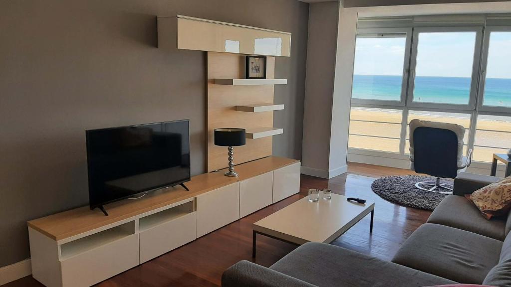 een woonkamer met een tv en een bank en een tafel bij Egona - Bañeru 3 Vivienda en 1 línea de playa centro ciudad in Zarautz