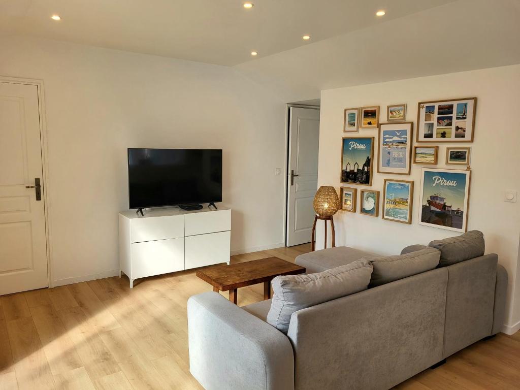 Una sala de estar con un sofá y un televisor de pantalla plana. en Gîte Les Pirouettes, en Pirou