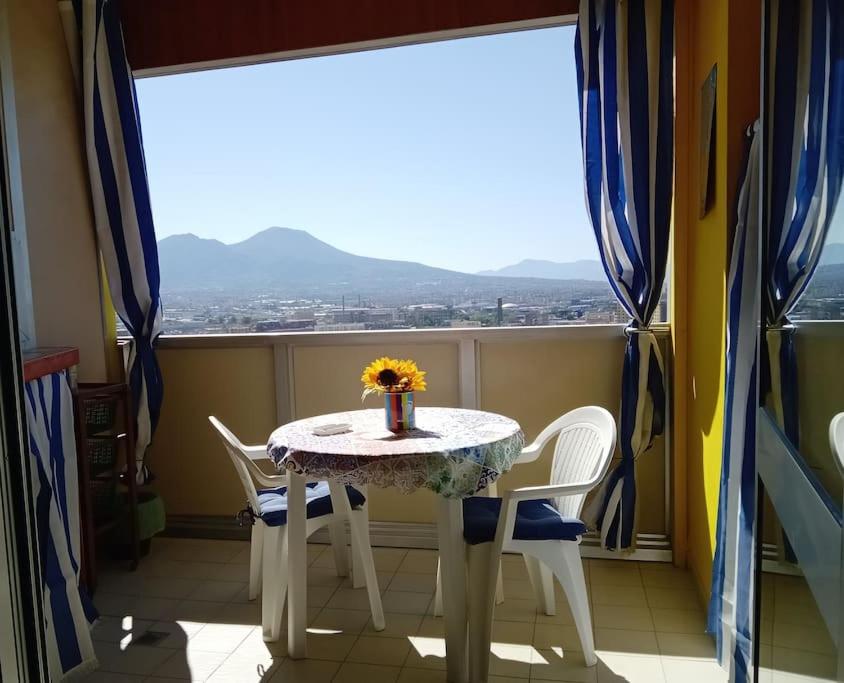 uma mesa e cadeiras num quarto com uma janela em Dreaming Vesuvio Napoli em Nápoles