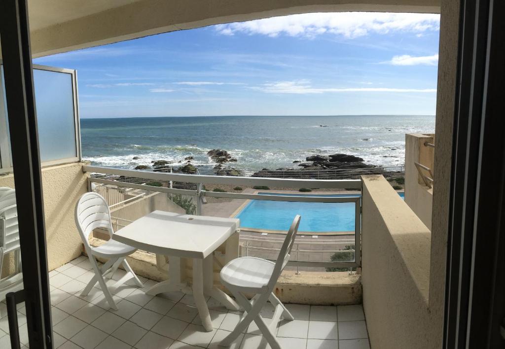 un balcon avec une table et des chaises et l'océan dans l'établissement Le Petit Bargeouri - Face mer avec piscine, à Les Sables-dʼOlonne