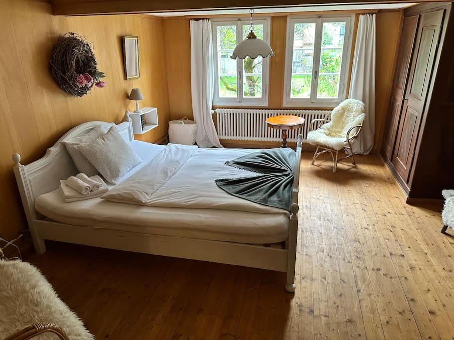 a bedroom with a bed and a chair and a window at Châlet Heidi, 2 Schlafzimmer grosser Garten in Wilderswil