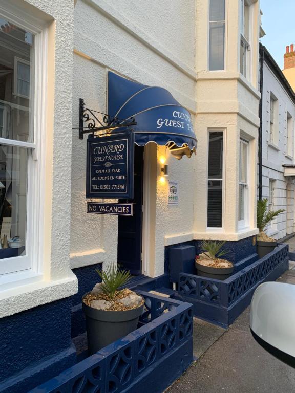 a cafe with an umbrella and plants in front of a building at Cunard Guest House in Weymouth