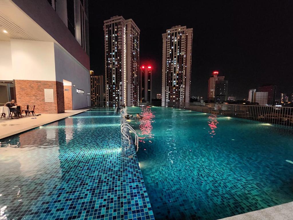 uma piscina com um horizonte da cidade à noite em Chambers Residences Suites KLCC em Kuala Lumpur