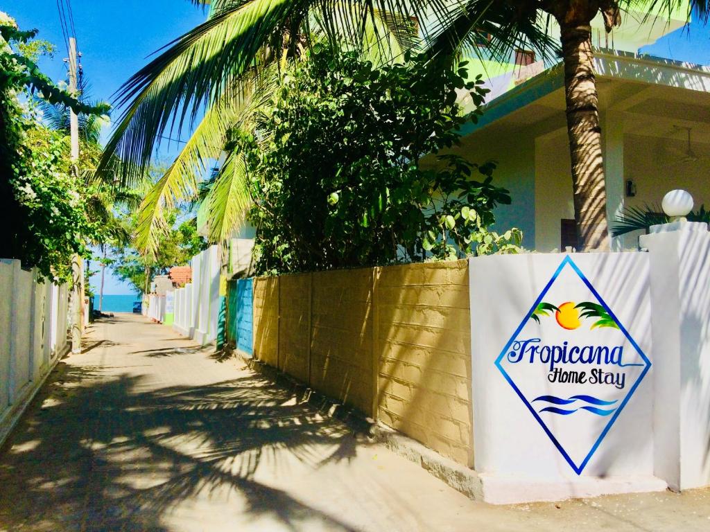un cartel en una pared frente a una casa en Tropicana Home Stay en Arugam Bay