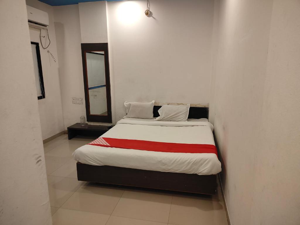 a bed in a white room with a red blanket at S Sai Inn in Shirdi