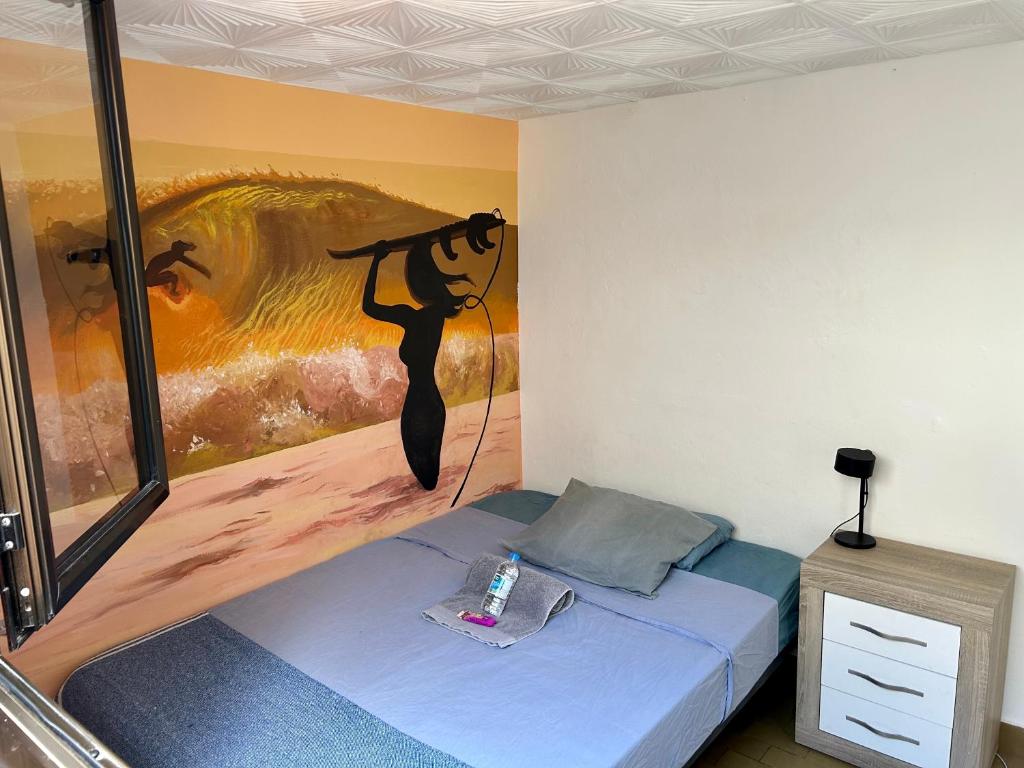 a room with a bed with a painting on the wall at Kite & Surf Nomad House in Las Palmas de Gran Canaria