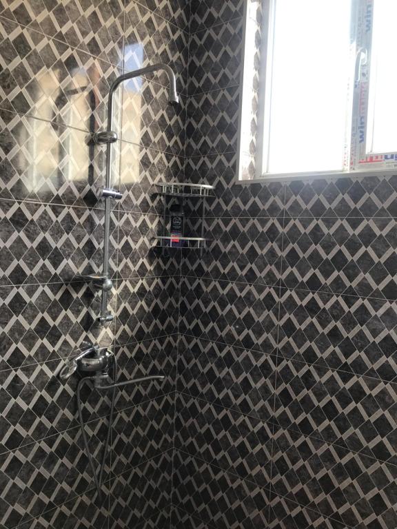 um chuveiro na casa de banho com uma parede de azulejos pretos em gaydi em Gori