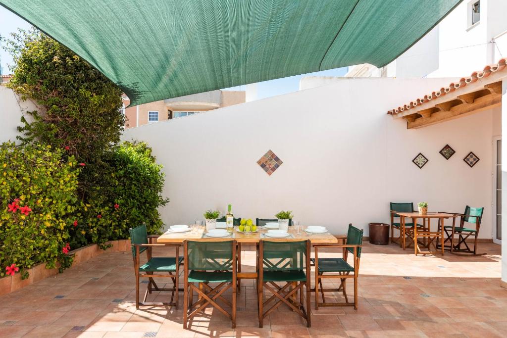une table et des chaises sur une terrasse avec un auvent vert dans l'établissement Ca Na Bel 4 bedroom house, Ciutadella, à Ciutadella