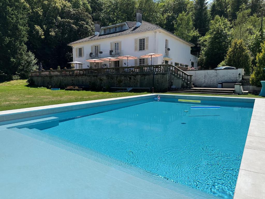 a large blue swimming pool in front of a house at Villa Moncoeur in Remiremont
