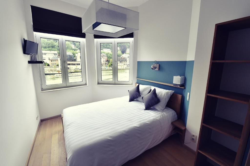 sypialnia z białym łóżkiem i 2 oknami w obiekcie Côté Sax bed and breakfast w mieście Dinant