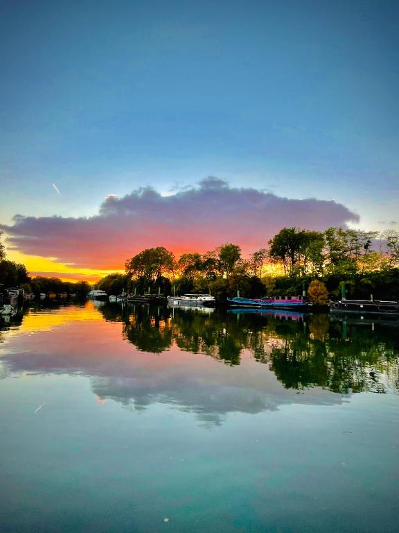 - une vue sur une rivière avec un coucher de soleil en arrière-plan dans l'établissement Cabine sur péniche à Bagatelle, à Paris