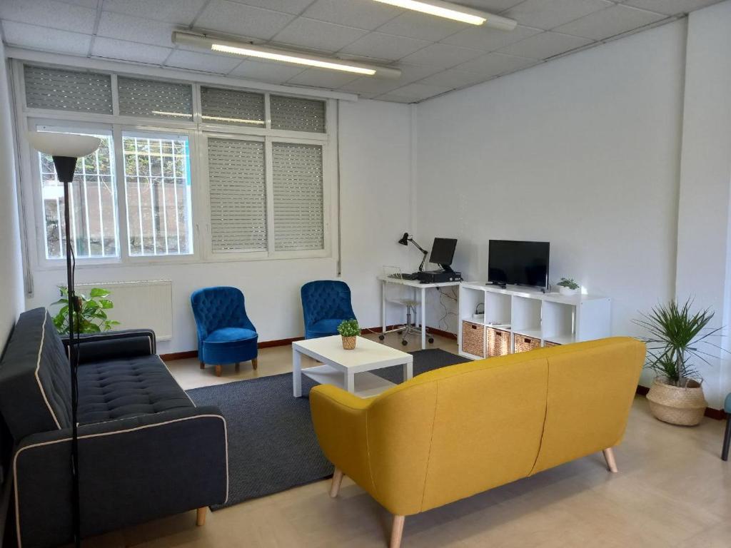 una oficina con sofá amarillo y sillas azules en Casa Margarida, en Allariz