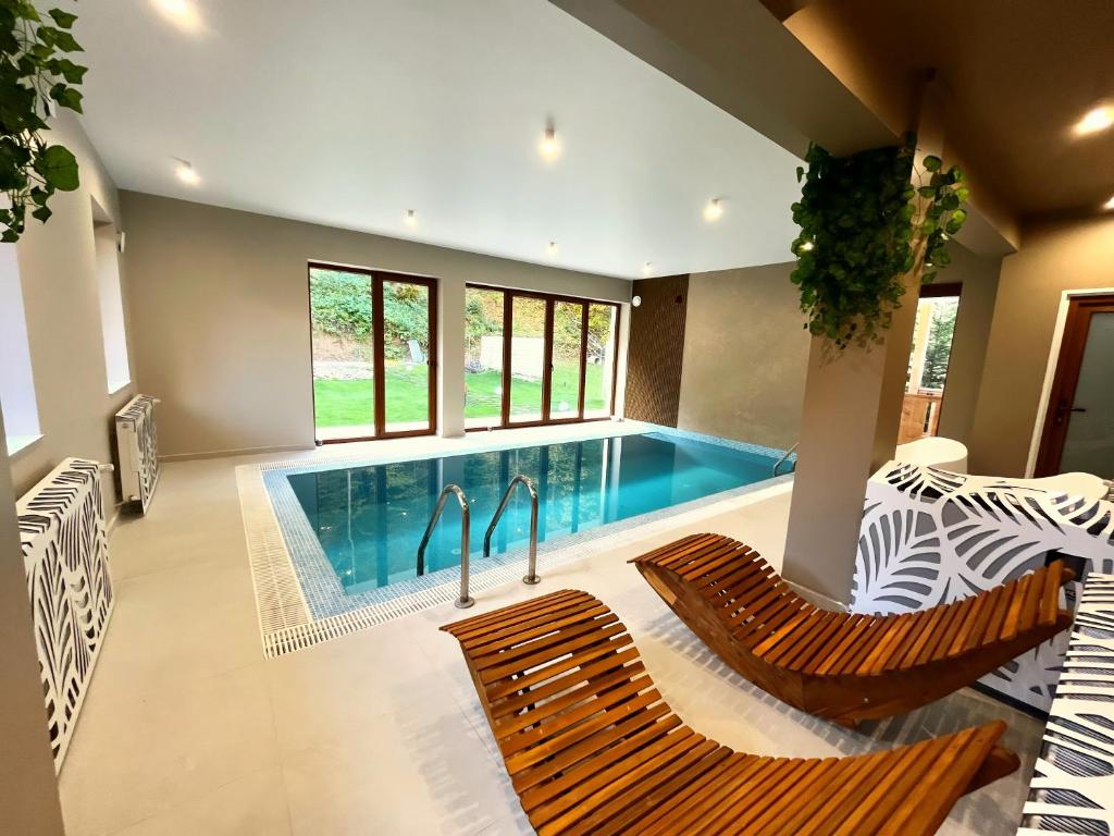 a swimming pool in a house with two chairs at Casa Forrest & SPA in Muntele Săcelului