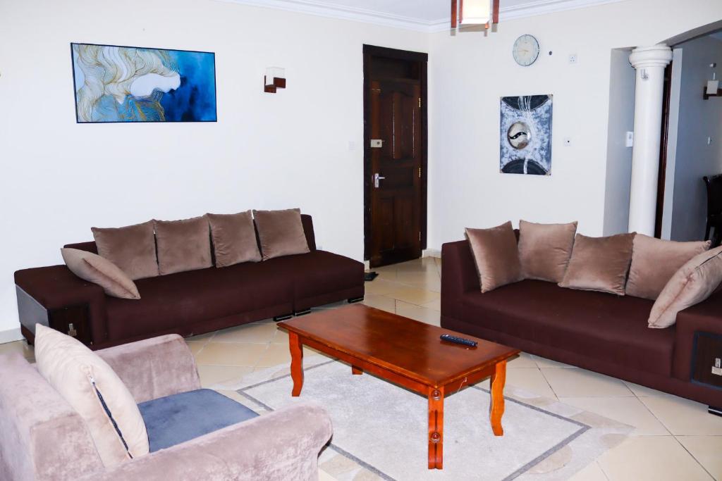 a living room with two brown couches and a coffee table at Gifts Aden apartments in Mombasa