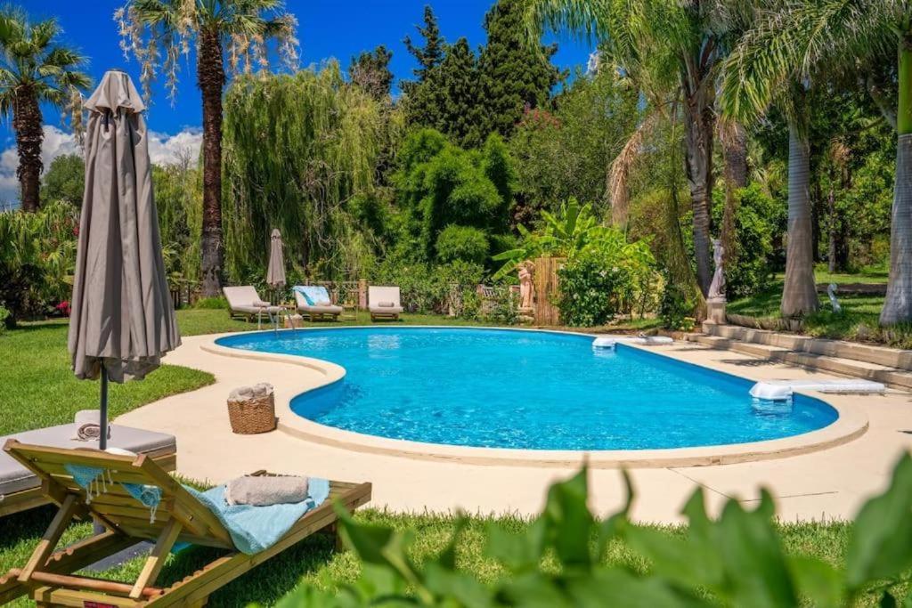 una piscina en un patio con sombrilla en Gaia Residences with lush garden and pool, en Argostoli