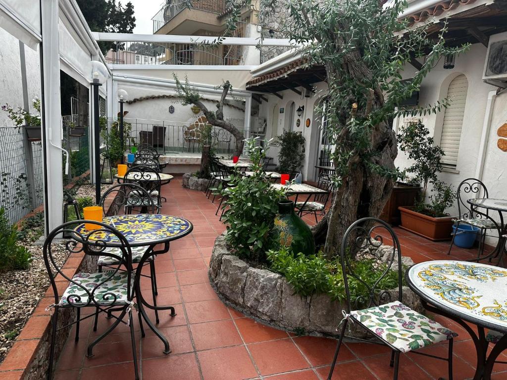 an outdoor patio with tables and chairs and a tree at Taormina Garden Hotel in Taormina